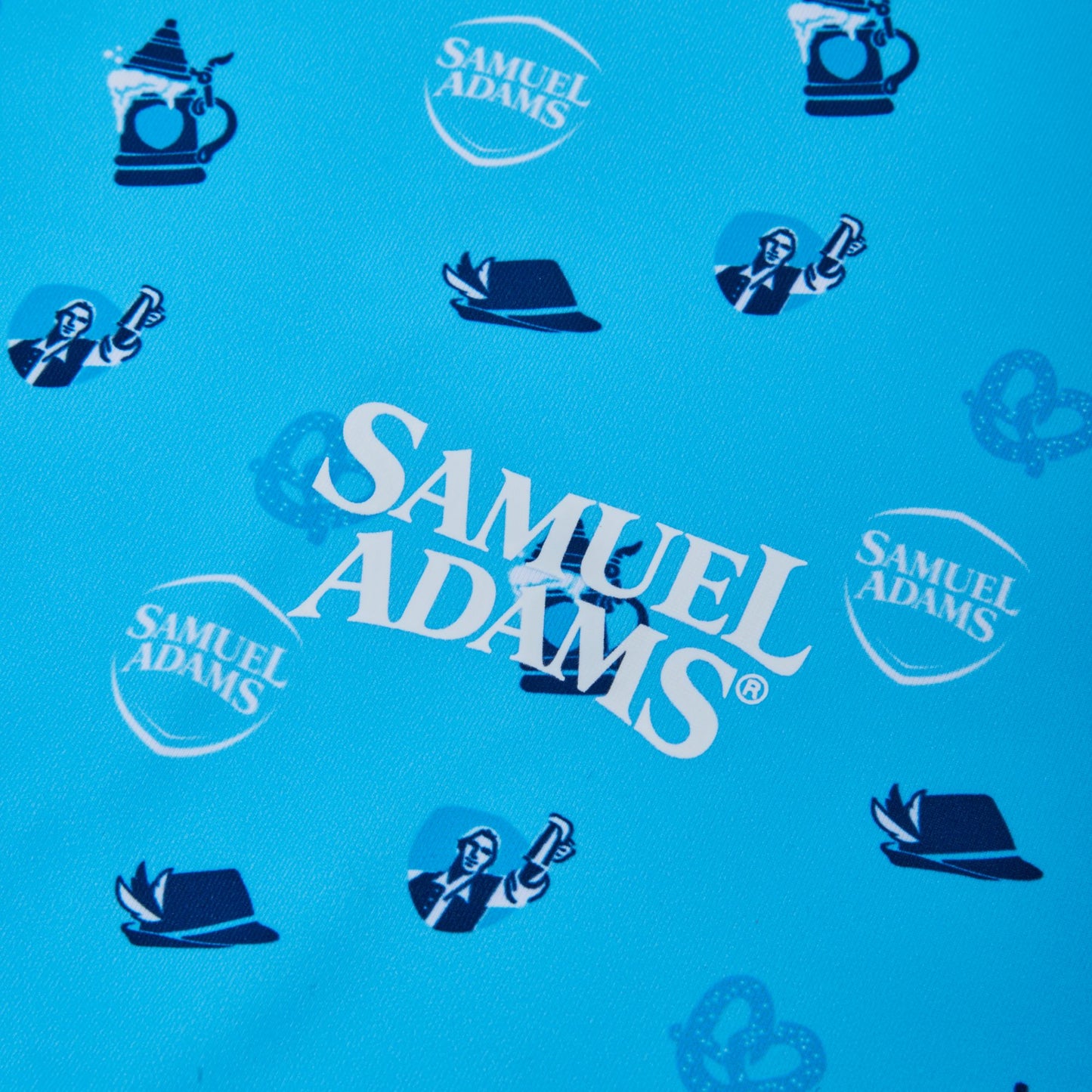 A close-up of a blue fabric featuring a repeating pattern of Samuel Adams logos, beer mugs, and Octoberfest hats.