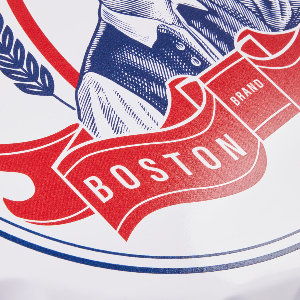 Close-up of a printed graphic on a white surface featuring a navy blue illustrated figure, a red ribbon banner with the word BOSTON in white, and the word BRAND on a small red box.