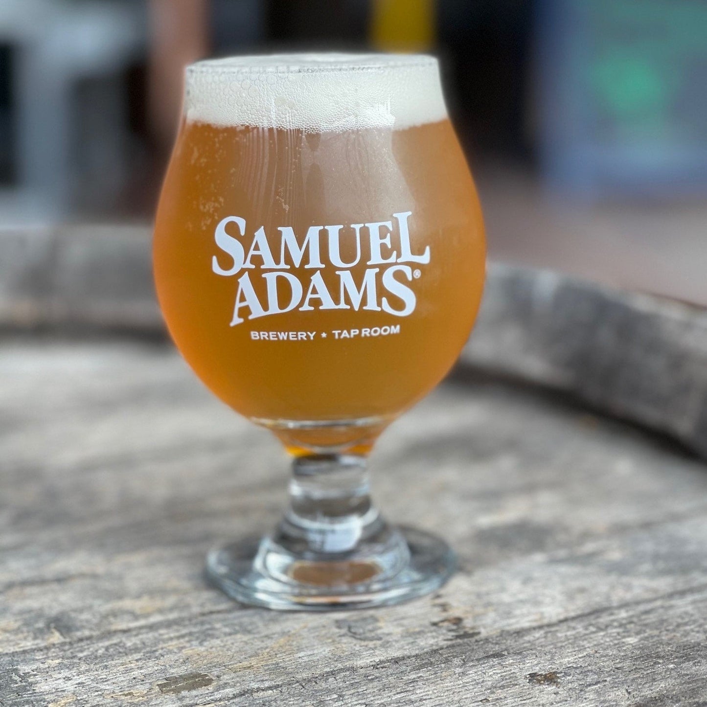 A 13oz Goblet Glass filled with beer that has the Samuel Adams logo printed in white with the words "brewery" and "taproom" printed under it.