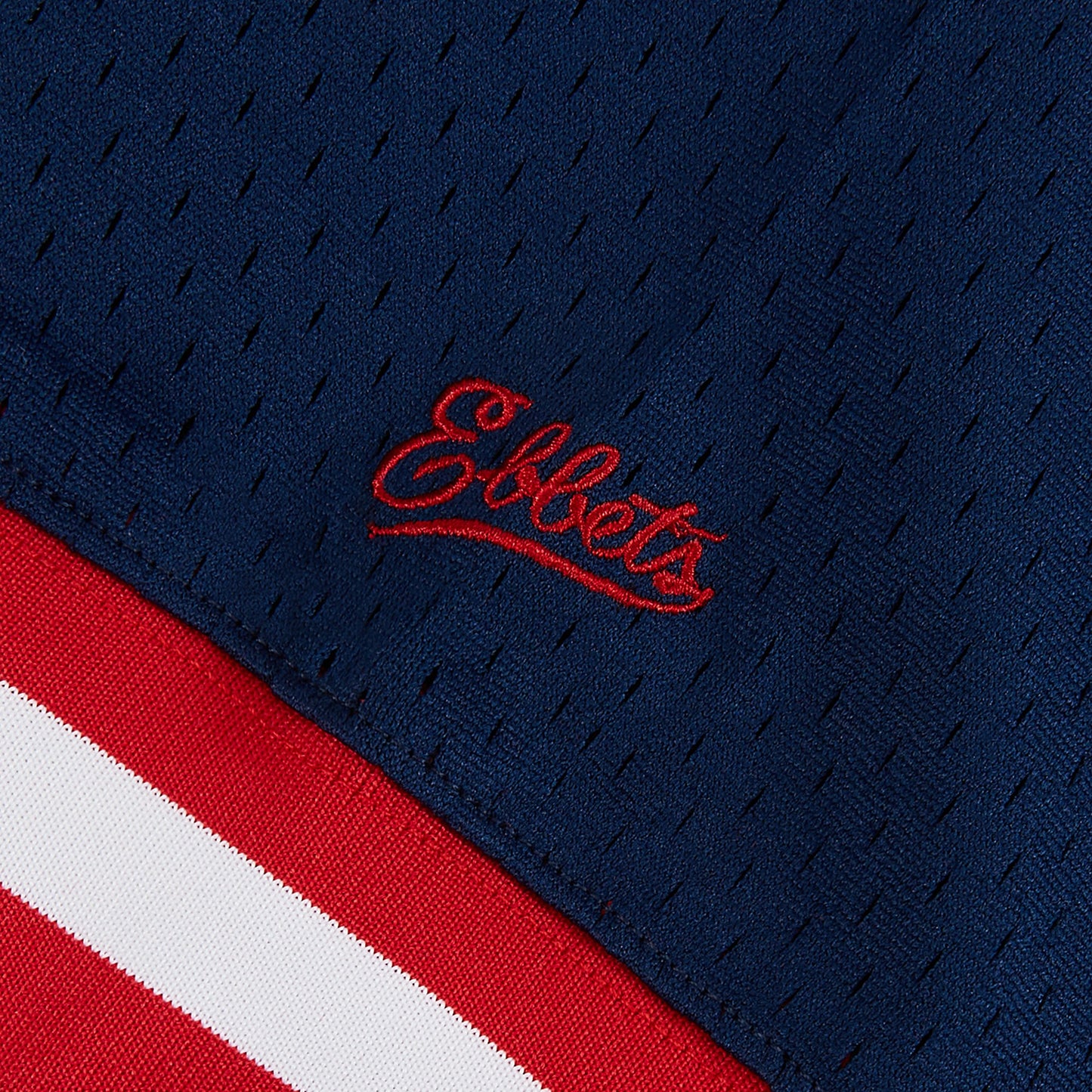 Close-up of a blue sports jersey with red and white accents and 'Ebbets' logo.