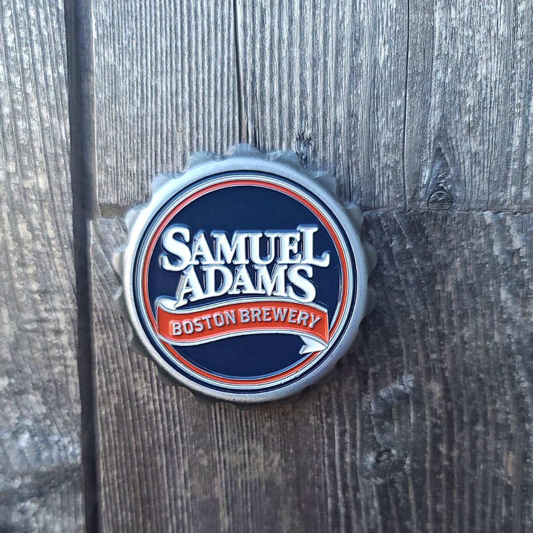 A metal bottle cap magnet with the Samuel Adams Boston Brewery logo in white and red against a navy blue background