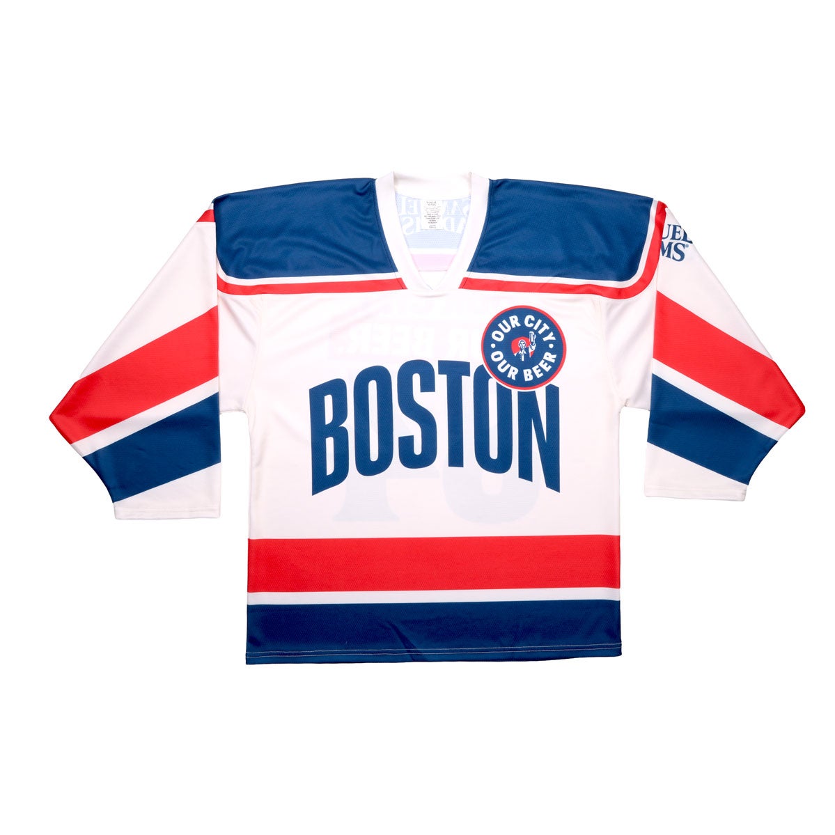 Base of jersey is white with blue and red patterns on the arms, waist, and shoulders. Centered "Boston" is written in blue, with a circle badge which features "Our City, Our Beer" and a red shield with Sam Adams hoisting a beer in the center of it. The Samuel Adams logo is featured in blue on the upper left arm.