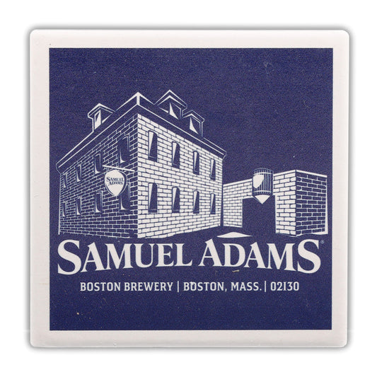 Coaster with a navy background and a white illustration of the Sam Adams Boston Brewery with the Samuel Adams logo under it and a white frame, is made of absorbent ceramic tile with a durable cork backing.