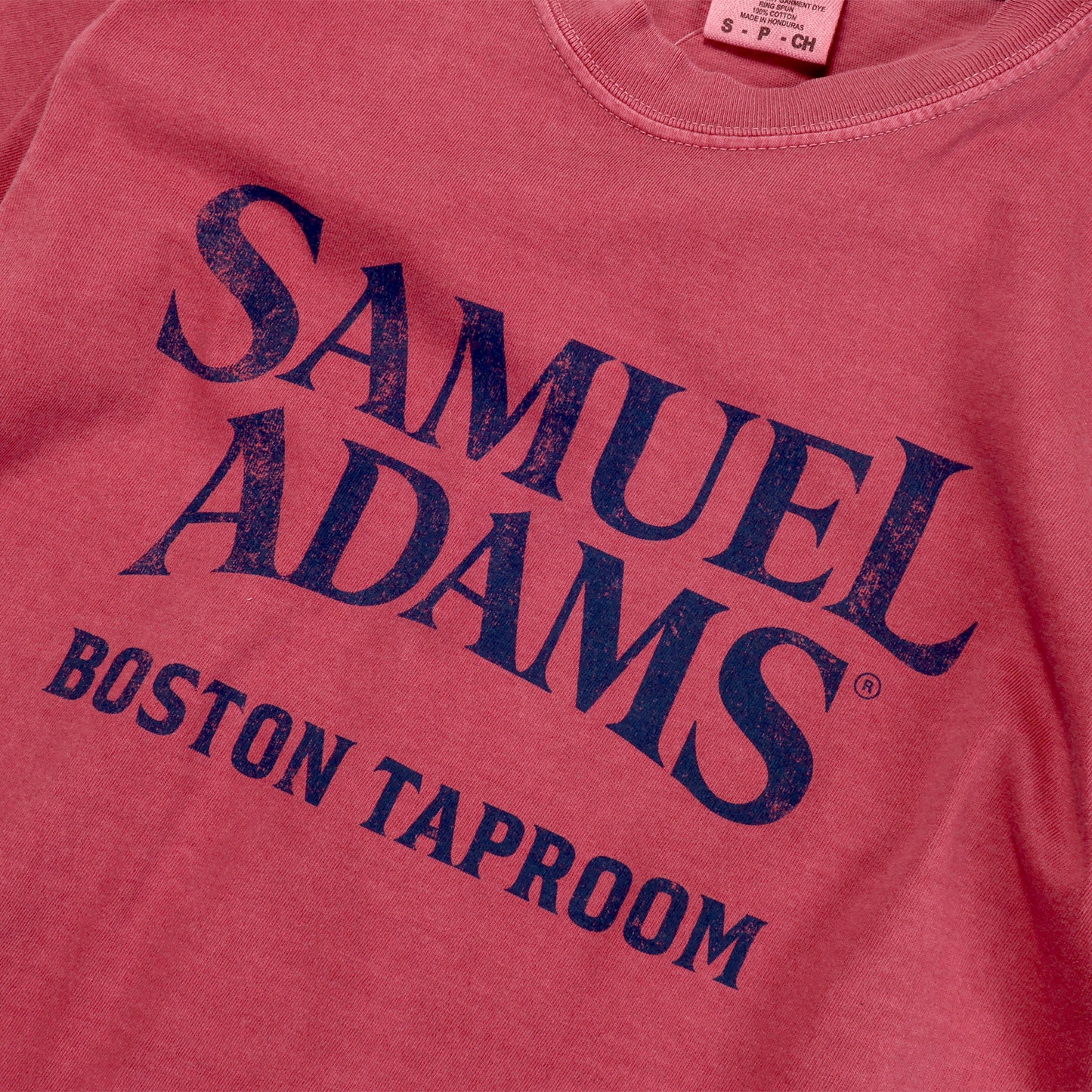 Close up of Brick Red Short Sleeve Statue Tee with a Navy Samuel Adams Boston Taproom Logo