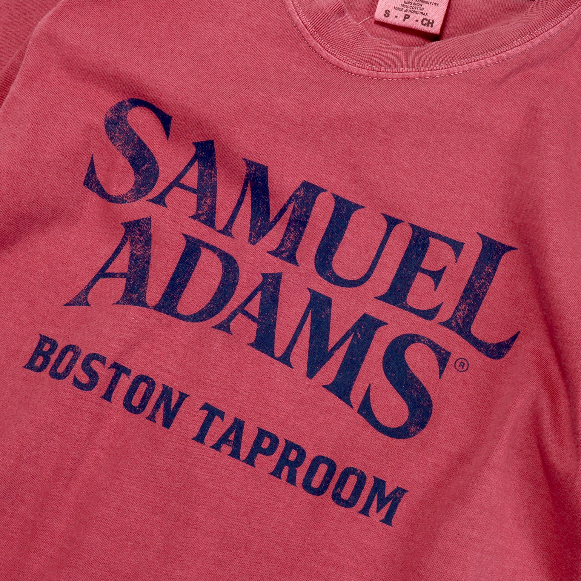 Close up of Brick Red Short Sleeve Statue Tee with a Navy Samuel Adams Boston Taproom Logo