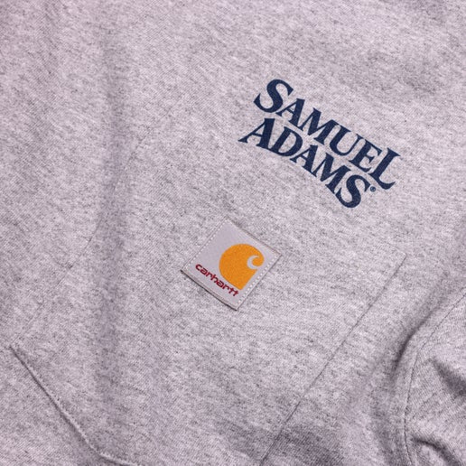 Close-up of the chest pocket showing the Carhartt patch and Samuel Adams logo.