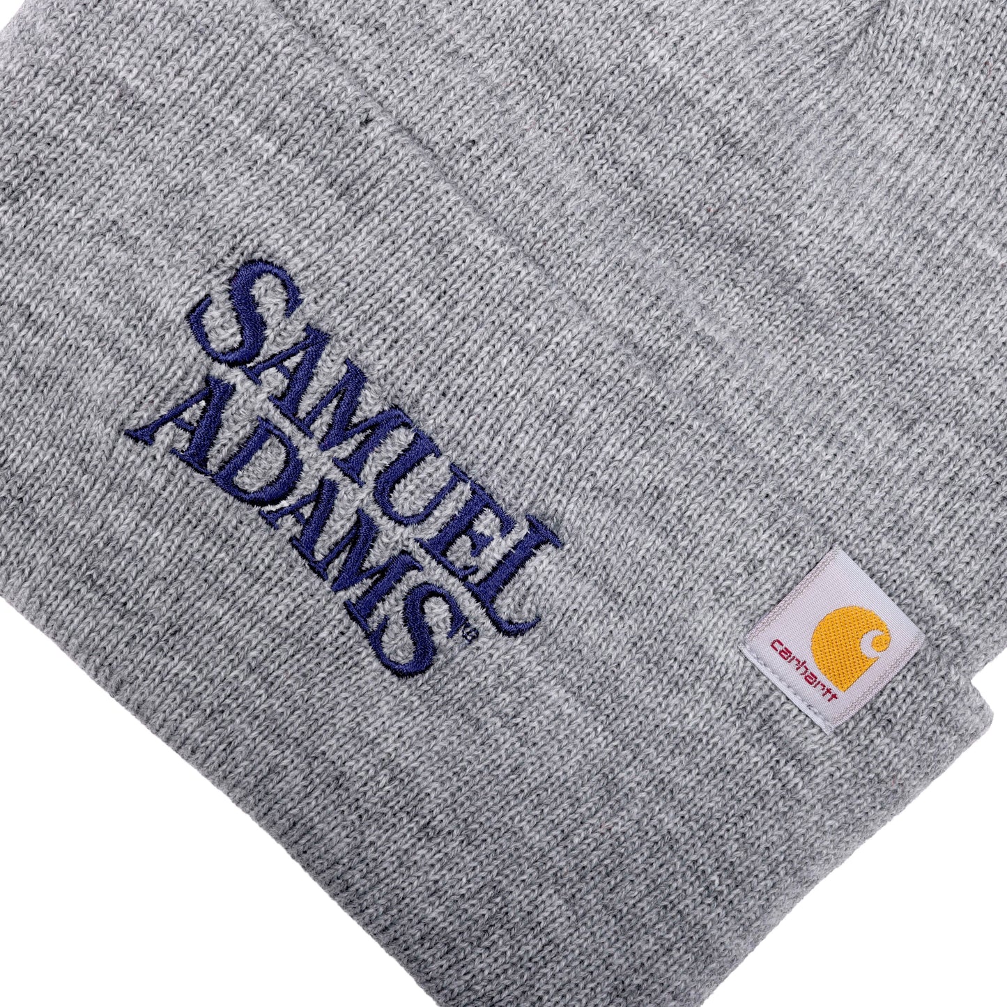 Close-up of fold over, features Samuel Adams written logo in navy blue. Small Carhartt logo patch is located on the top left of fold over.