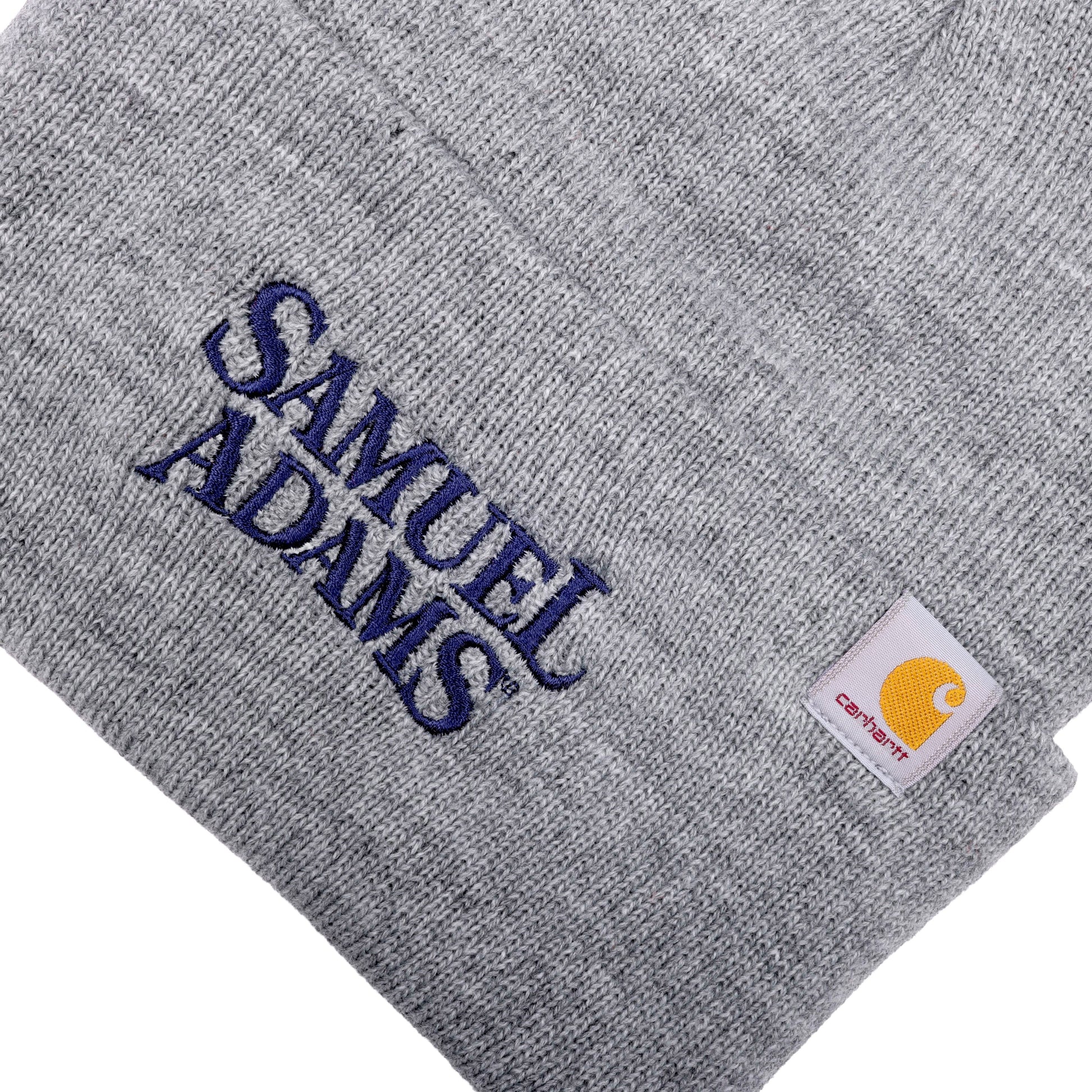 Close-up of fold over, features Samuel Adams written logo in navy blue. Small Carhartt logo patch is located on the top left of fold over.