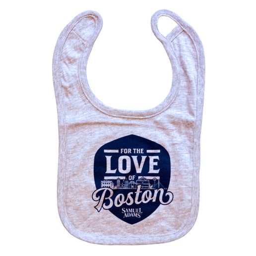 Grey bib with a blue shield in the center. Sheild features writing "For the Love of Boston" with the Sam Adams logo at the bottom of it. The Boston skyline is featured in between the words.