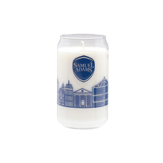 This can-shaped glass has a navy illustration of the Boston skyline around the outside of it with the Samuel Adams classic shield logo above it. The glass is filled with a white wax candle.