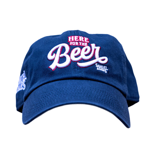 Front view of navy hat with writing "Here for the Beer" in white and outlined in red. On the bottom left of that writing is the Samuel Adams logo in white.