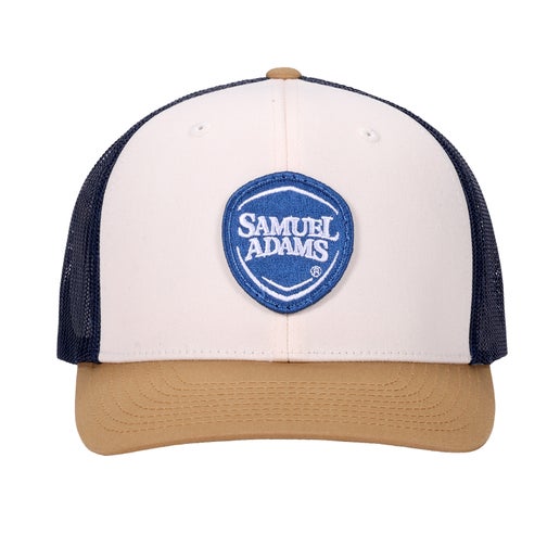 Samuel Adams trucker hat with a gold-colored rim, navy mesh back, and a solid white front with a blue Samuel Adams shield logo.