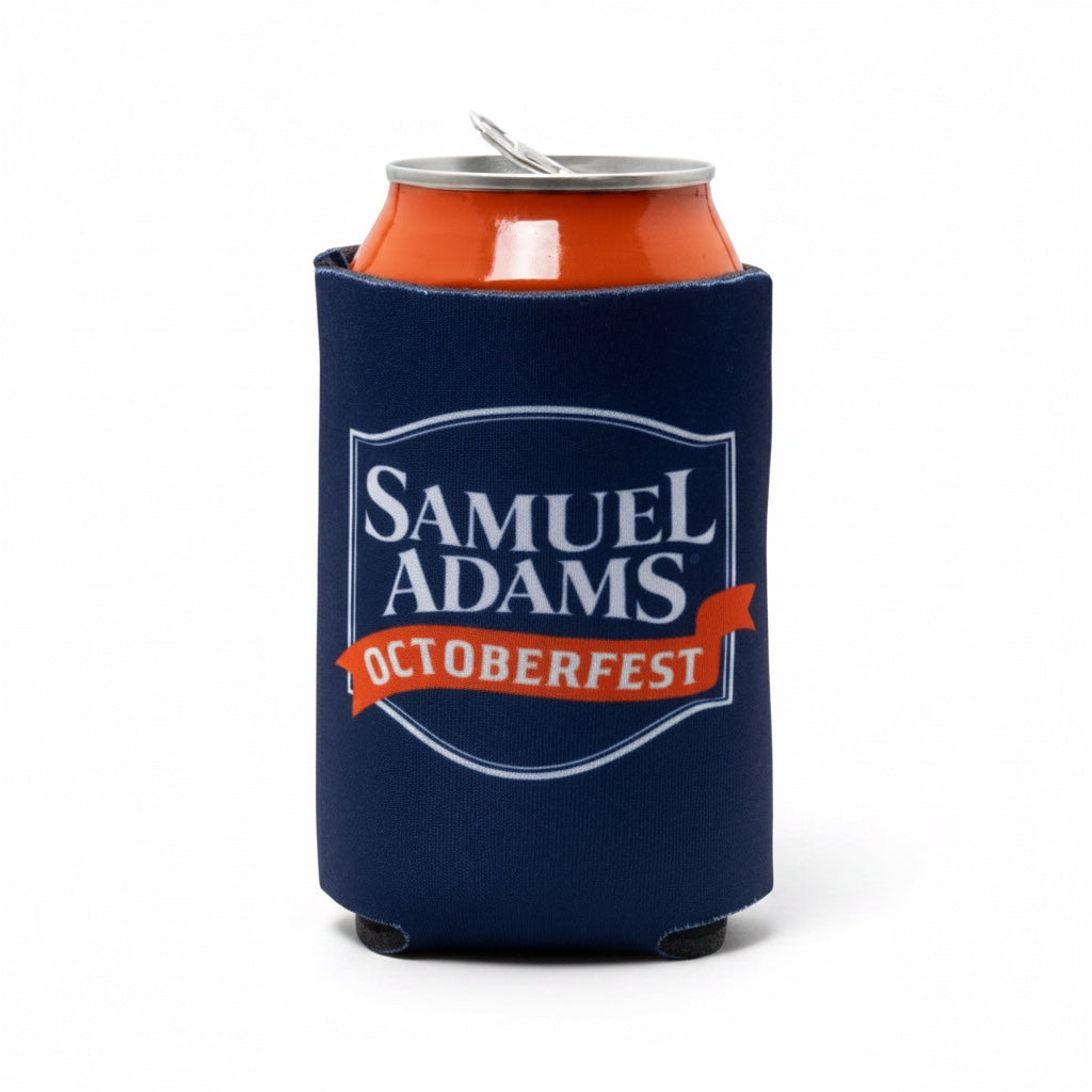 A navy blue neoprene can cooler sleeve featuring the Samuel Adams Oktoberfest logo, holding an orange beverage can on a white background.