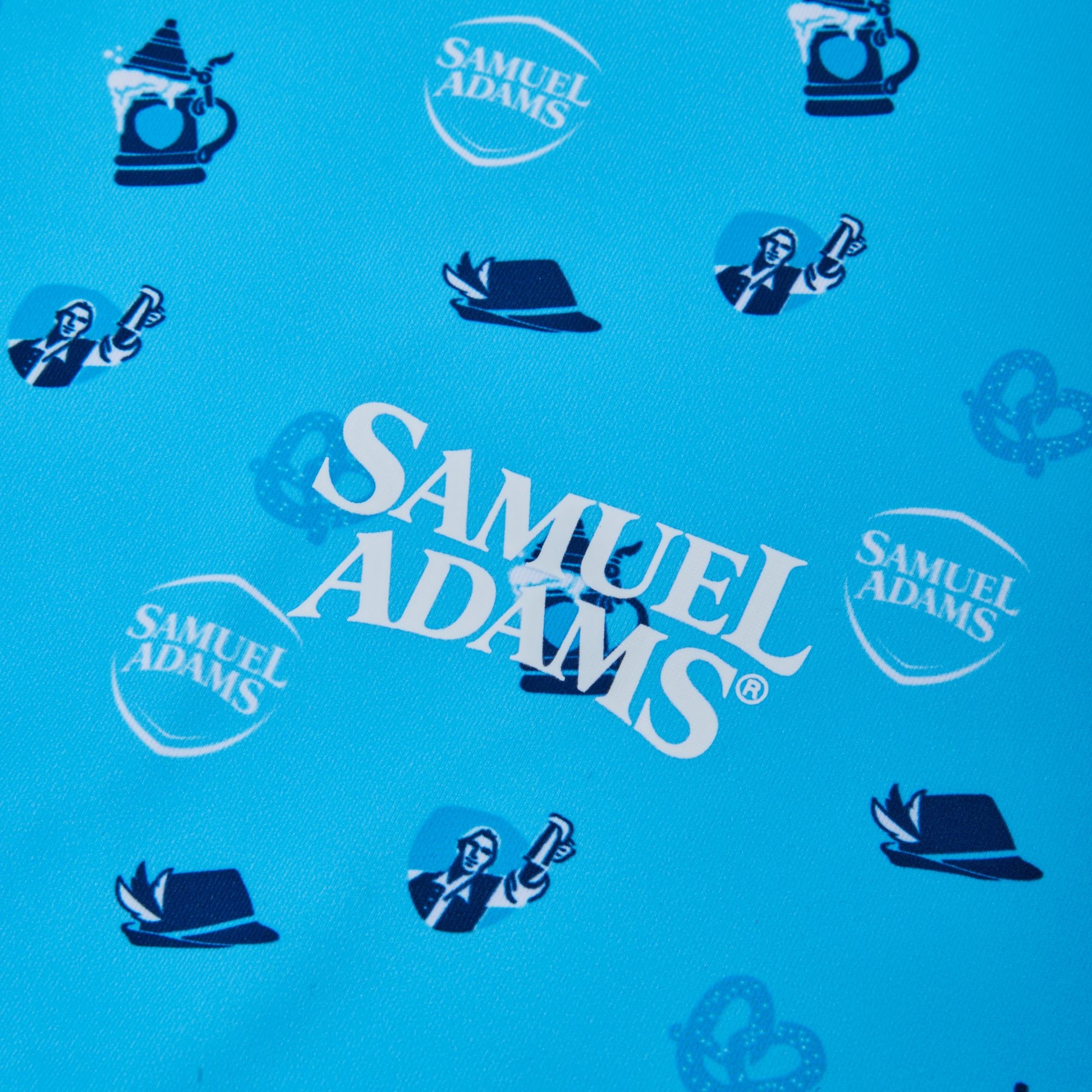 A close-up of a blue fabric featuring a repeating pattern of Samuel Adams logos, beer mugs, and Octoberfest hats.