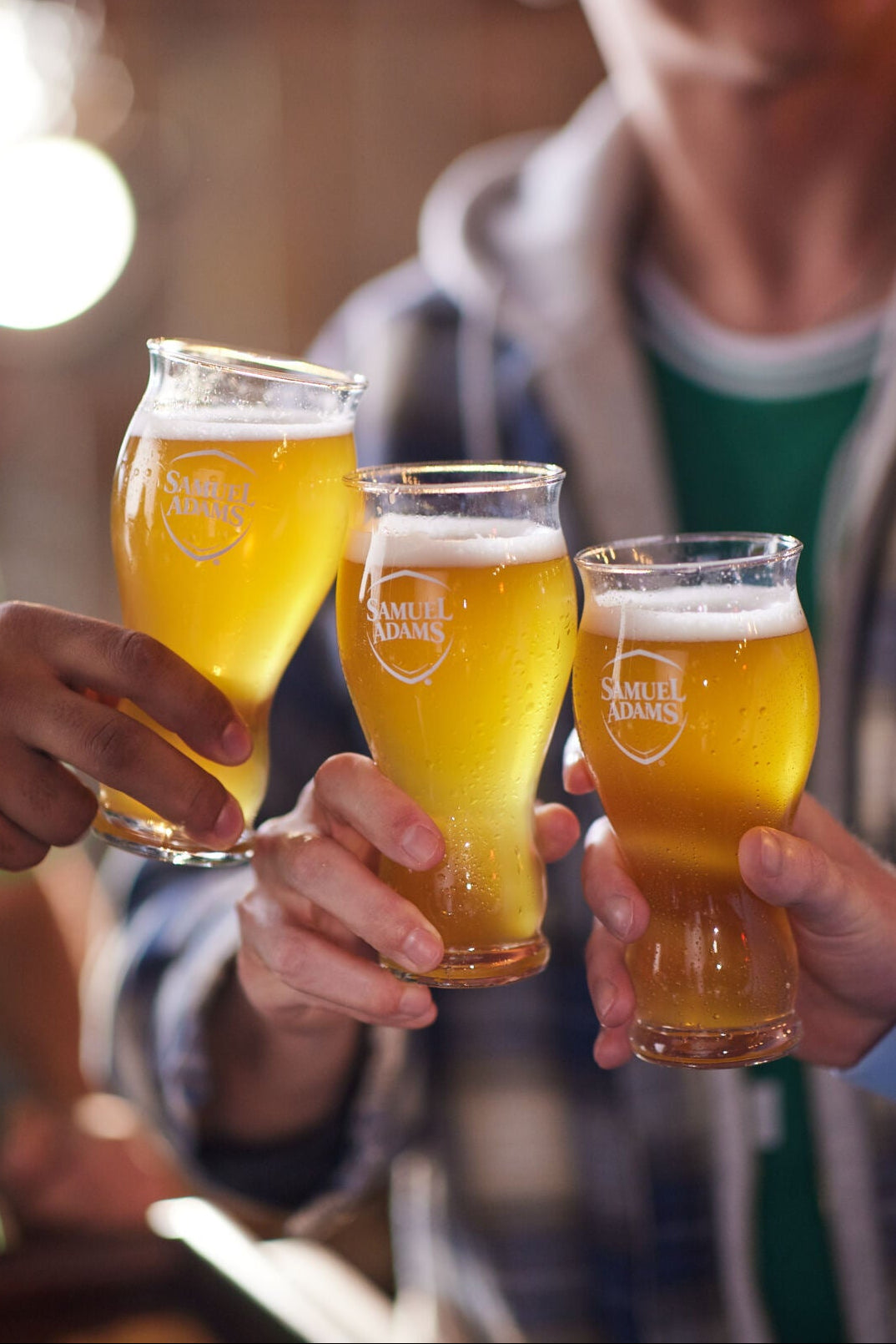 Three people toasting with glasses of beer in a casual setting