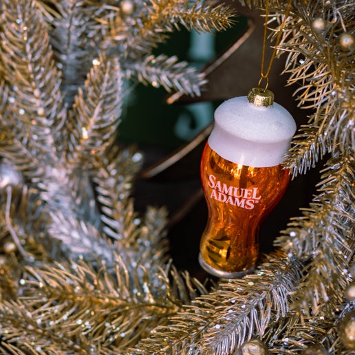 A glass ornament modeled after a perfect pint glass full of Sam Adams beer. Pictured here on a Christmas tree.