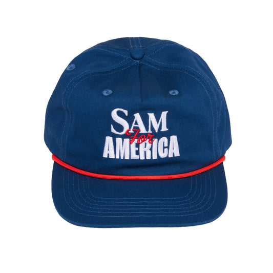 Navy blue Samuel Adams 250 rope baseball hat with white “SAM AMERICA” embroidered text, red script “for” detail, and red rope accent across the brim