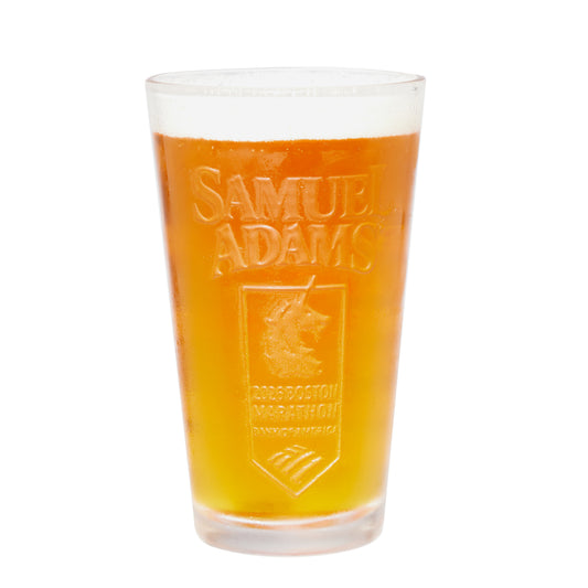 Marathon embossed shaker pint glass filled with golden beer, featuring a raised Samuel Adams logo and Boston Marathon insignia on clear glass, isolated on white background