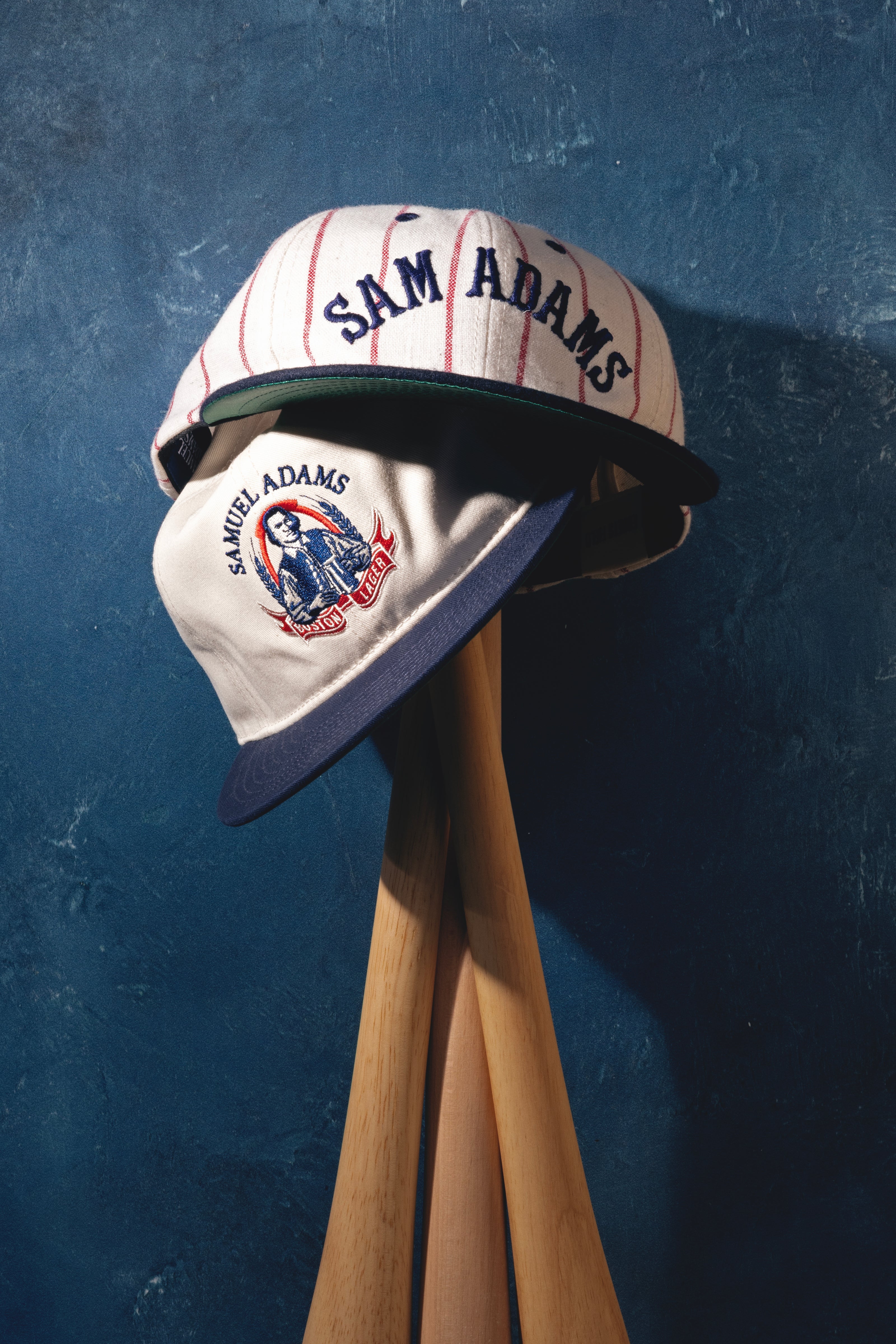 Sam Adams baseball cap on a wooden stand against a blue textured background