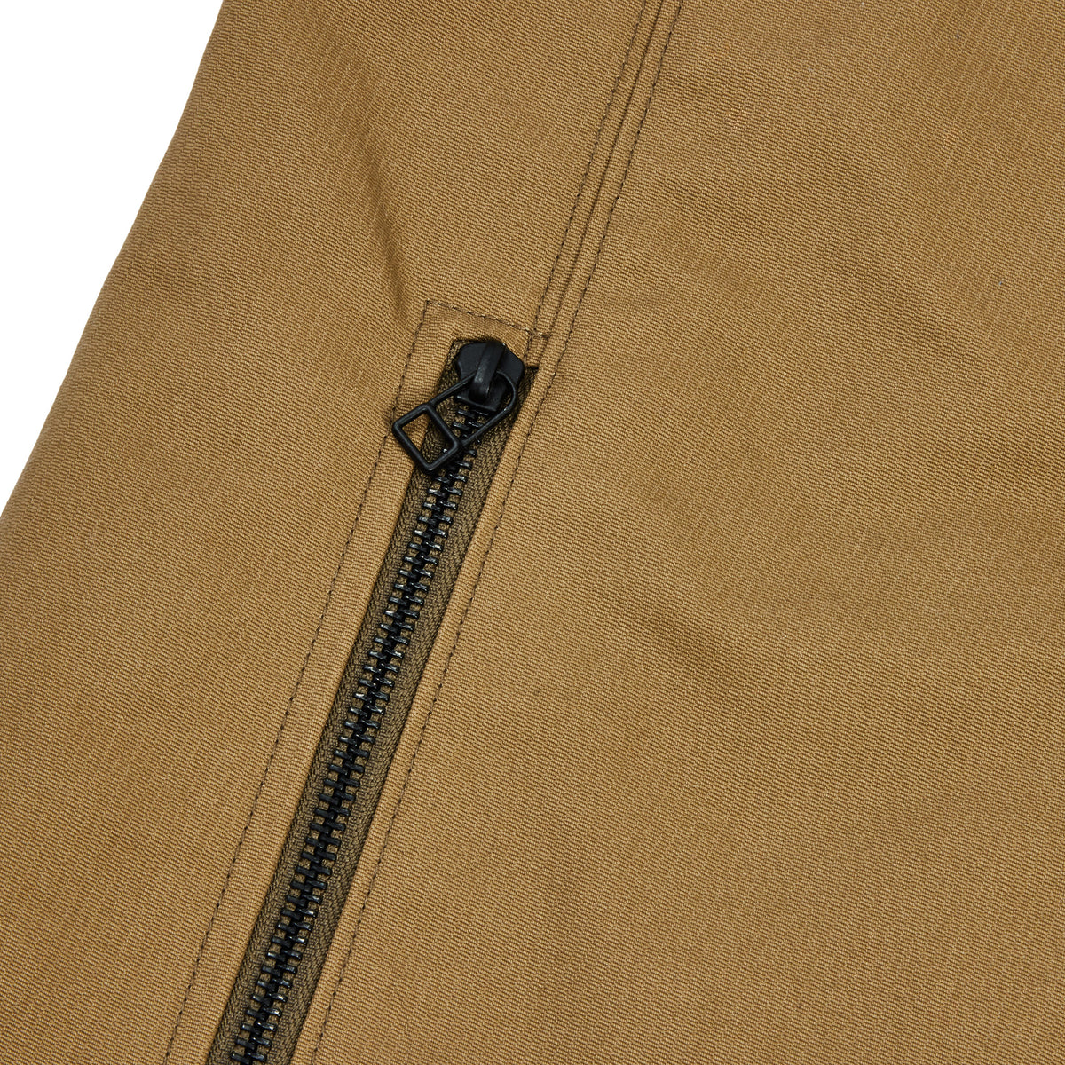 Close-up of a tan fabric garment with a black zipper and black zipper pull on a white background.