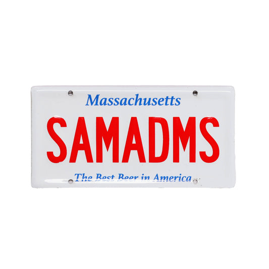 White bike tacker designed to look like a license plate with "SAMADMS" designed in red text. Header reads, "Massachusetts", bottom text reads, "The Best Beer in America" in small blue type. 