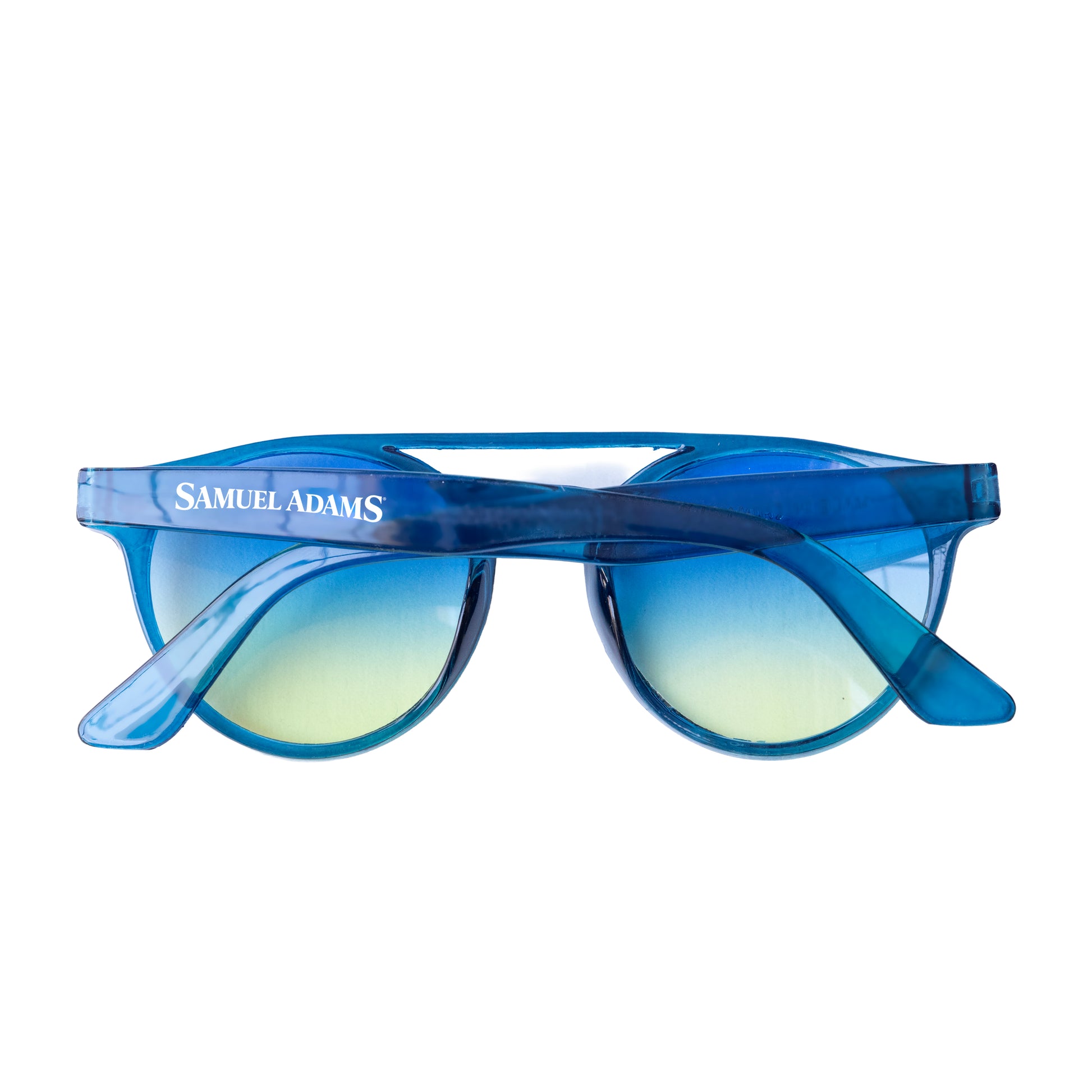 Folded Samuel Adams sunglasses with translucent blue frame, gradient blue and yellow lenses, and white “Samuel Adams” text printed on the outer arm