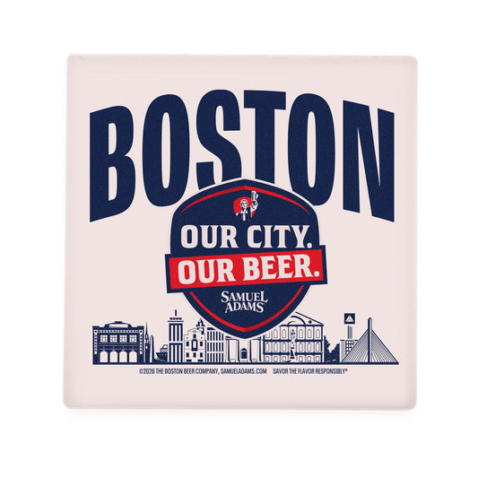 A square ceramic coaster featuring bold navy text reading “BOSTON” across the top. Below it is a navy and red shield‑style emblem with the Samuel Adams icon and the slogan “OUR CITY. OUR BEER.” in white and red lettering. The Samuel Adams logo appears beneath the shield. Along the bottom edge of the coaster is a stylized navy illustration of Boston landmarks, including iconic buildings and the Zakim Bridge. The coaster has rounded edges and a soft off‑white background