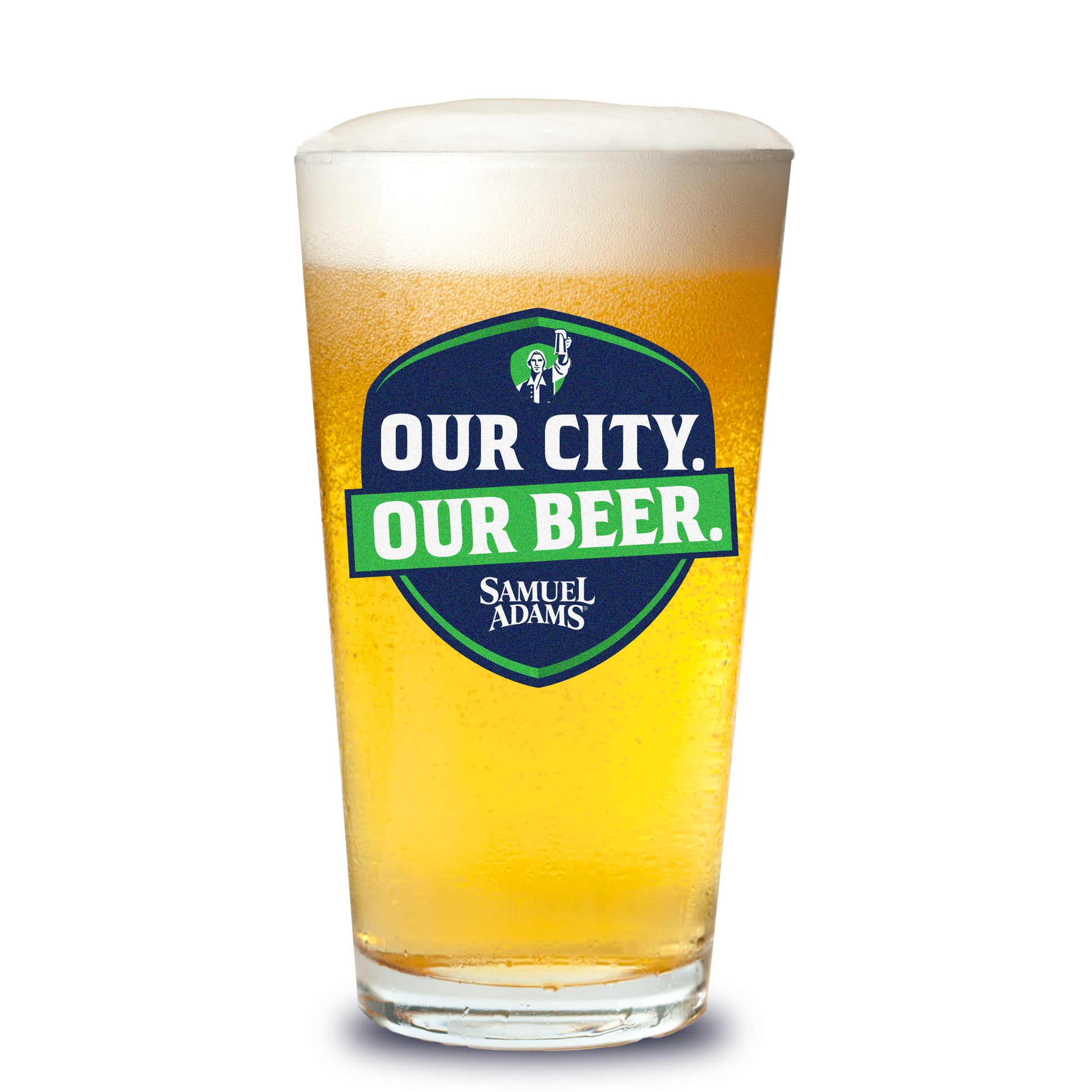A Samuel Adams pint glass filled with golden beer showing the navy shield logo with green accents that reads “OUR CITY. OUR BEER.” with the Samuel Adams icon and wordmark.