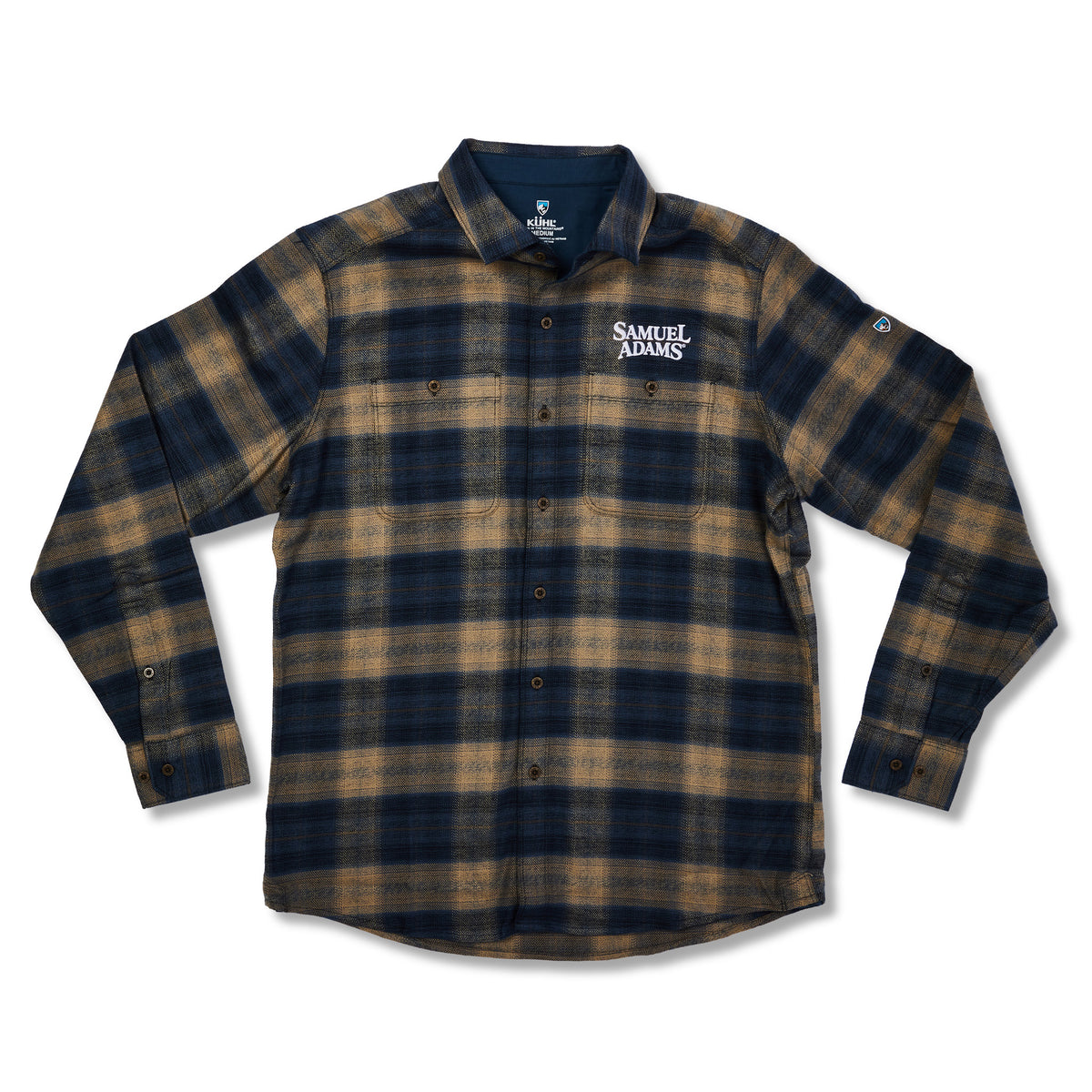 A long-sleeve button-up flannel shirt by Samuel Adams, featuring a dark navy and tan plaid pattern. The brand name 'SAMUEL ADAMS' is printed in white on the left chest, and a small logo is visible on the right sleeve cuff.