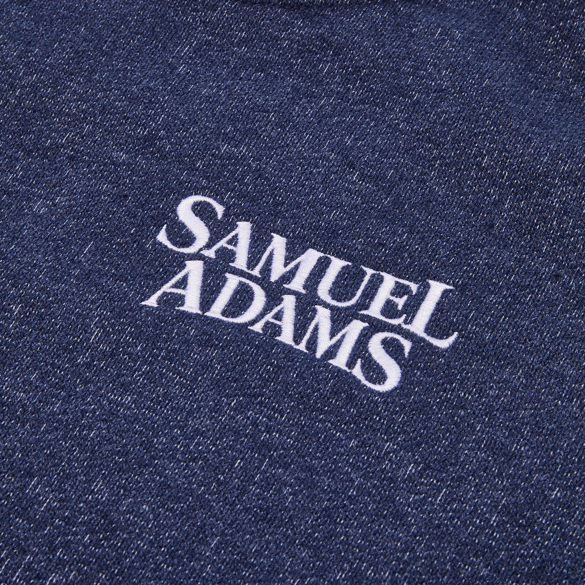 Close-up of a dark navy blue heathered fabric with white embroidered text reading 'SAMUEL ADAMS'.