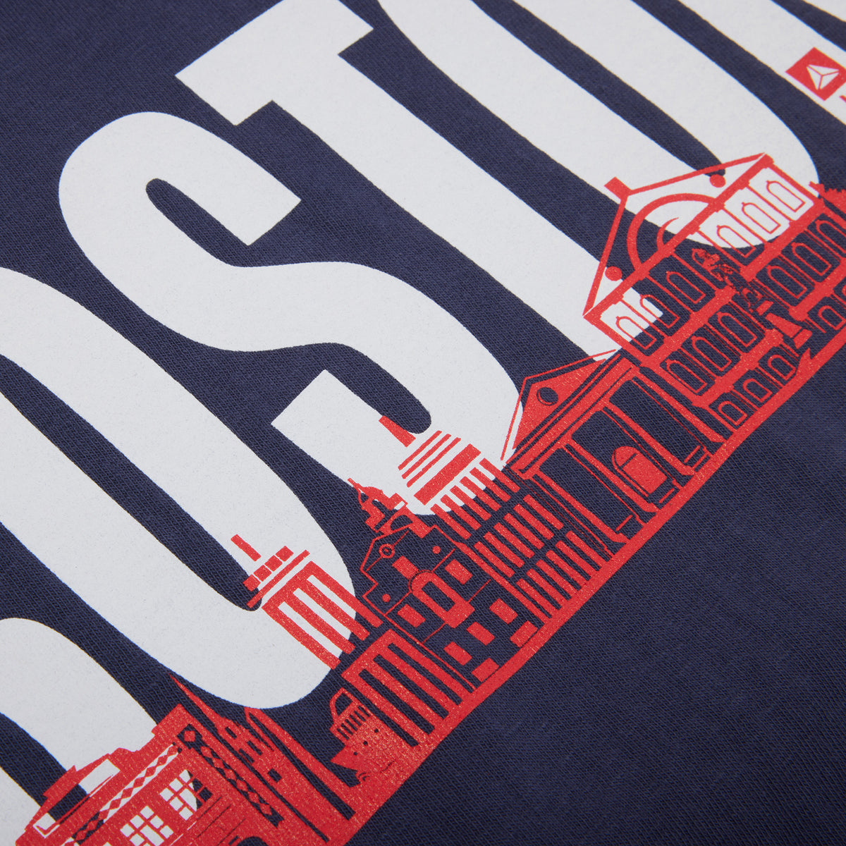 Close-up of a navy blue graphic print featuring large white letters and a red city skyline illustration.