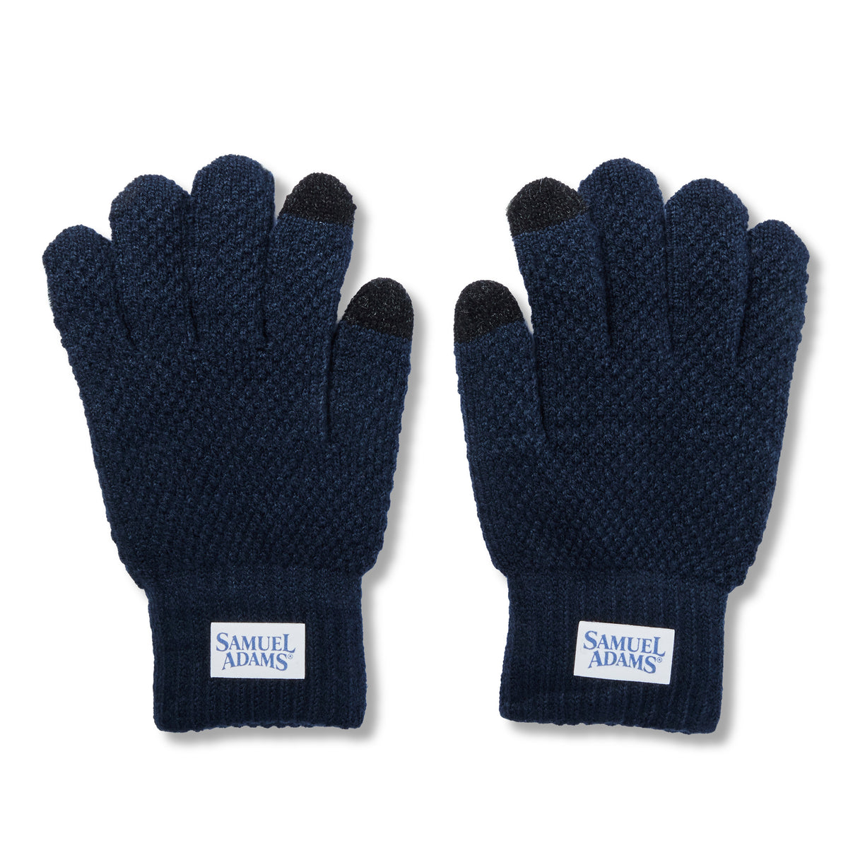 A pair of dark navy blue knit touchscreen gloves with black fingertips and a white brand label on the wrist reading 'SAMUEL ADAMS'.