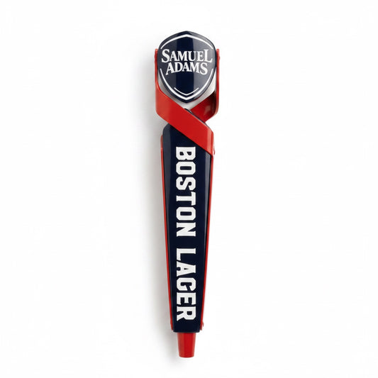 A tap handle with the Sam Adams logo written in white against a blue shield shaped piece. The shield is being held by two red shapes that cross and continue down the tap handle.  Boston Lager is written vertically in white across the blue body of the tap handle. There is a red   cylindrical shape at the bottom. 
