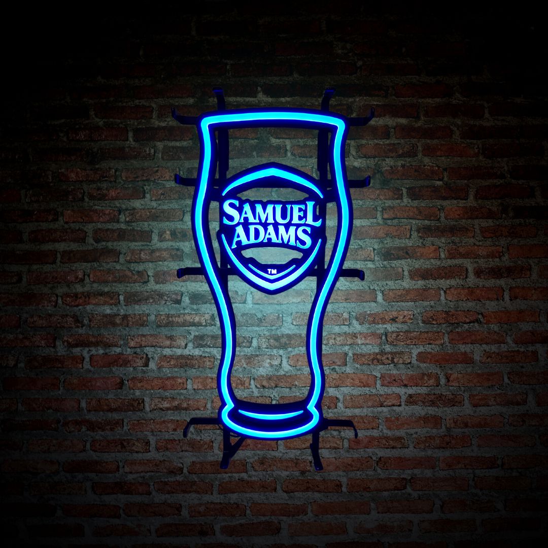 A Samuel Adams Pint LED with blue neon lighting. Pictured switched on against a brick wall.