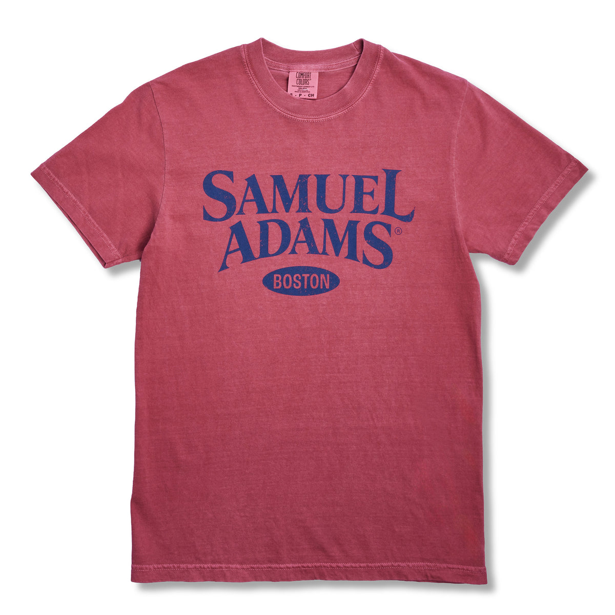 A short-sleeve crewneck t-shirt in a washed, heathered red-pink color, featuring a dark blue graphic print on the front that reads 'SAMUEL ADAMS BOSTON'.