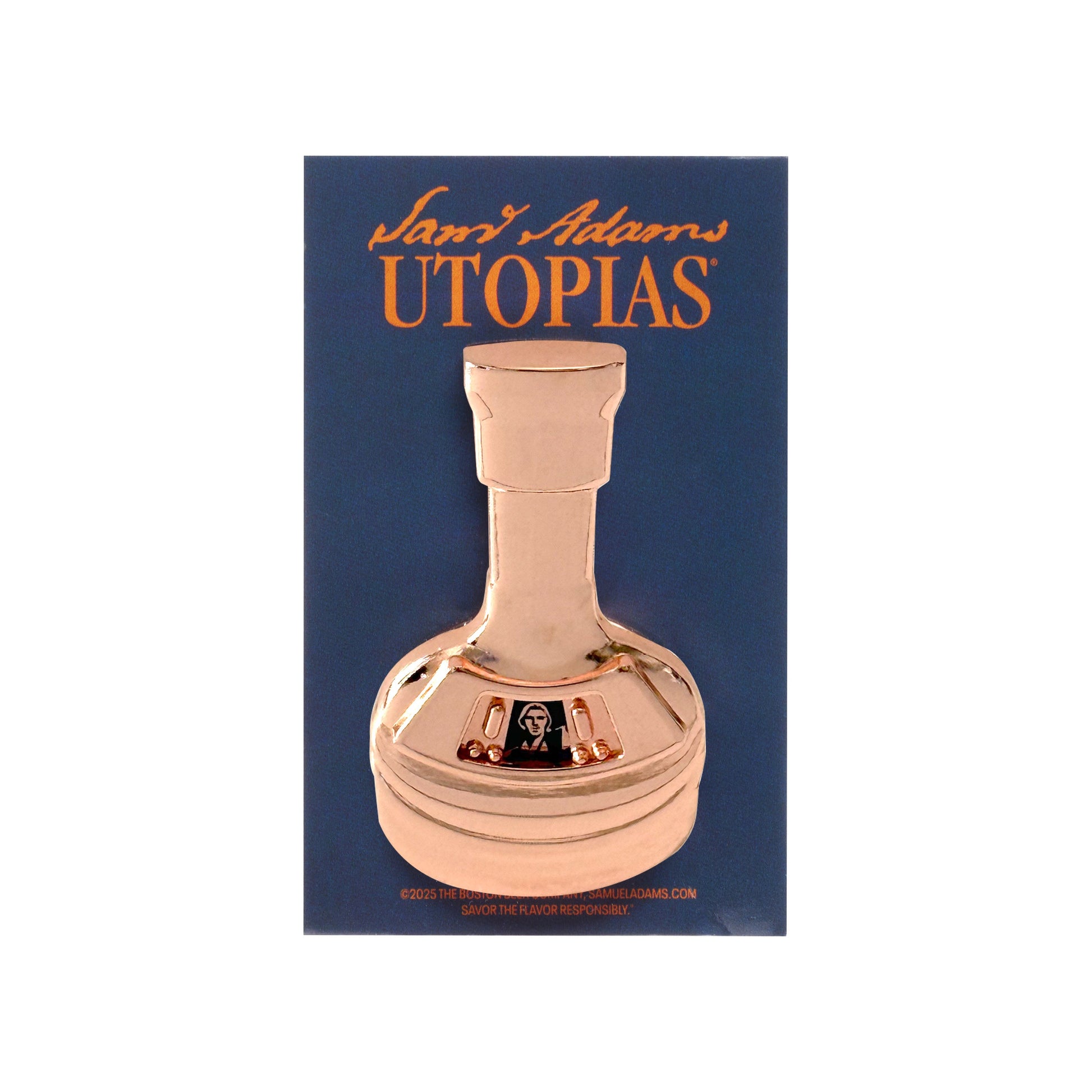 Pin pictured in the packaging. Pin is shaped like the Utopias limited edition bottle with a small image of a blue and white Sam Adams on the base.