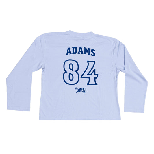 Blue long sleeve in a jersey style with writing in a darker blue. 'Name' on tee is Adams and number is 84. Under both the Samuel Adams logo is featured.