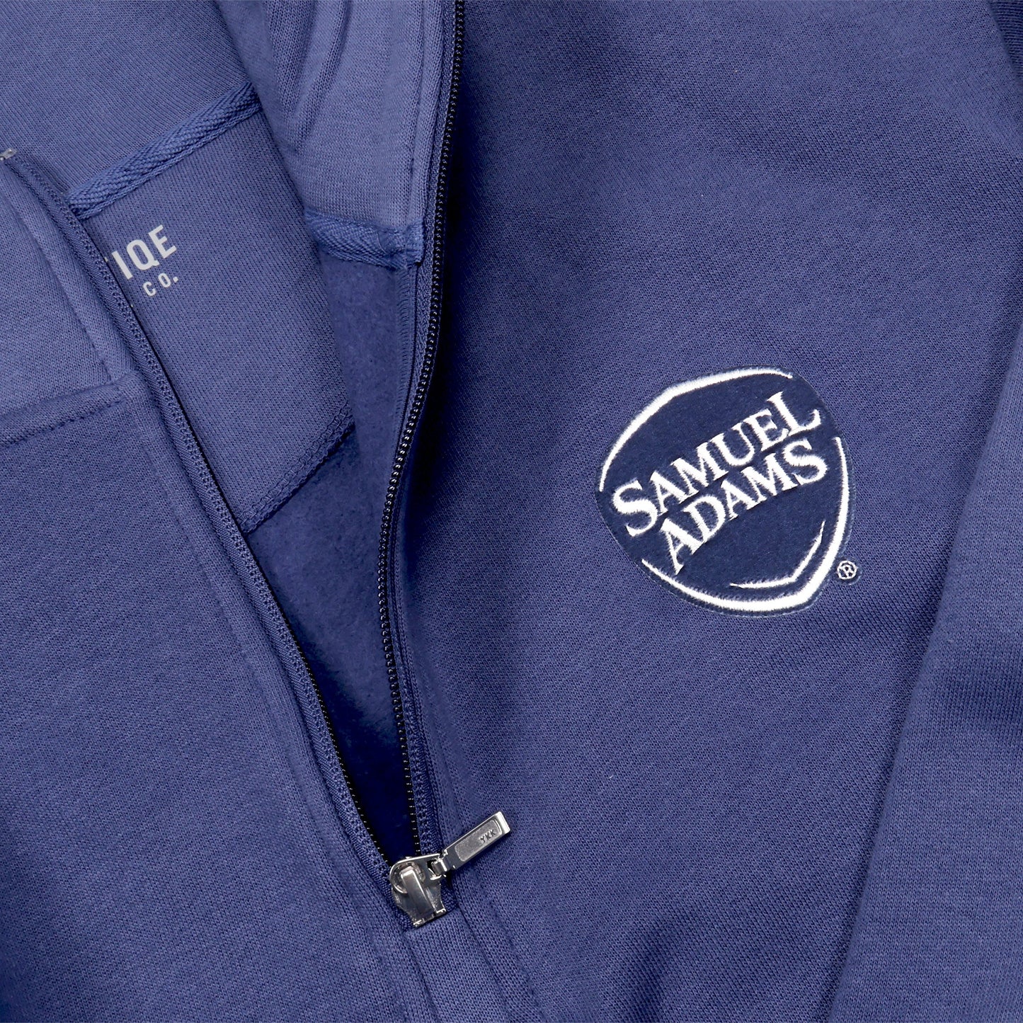 Close up of samuel adams logo on a blue quarter zip sweatshirt