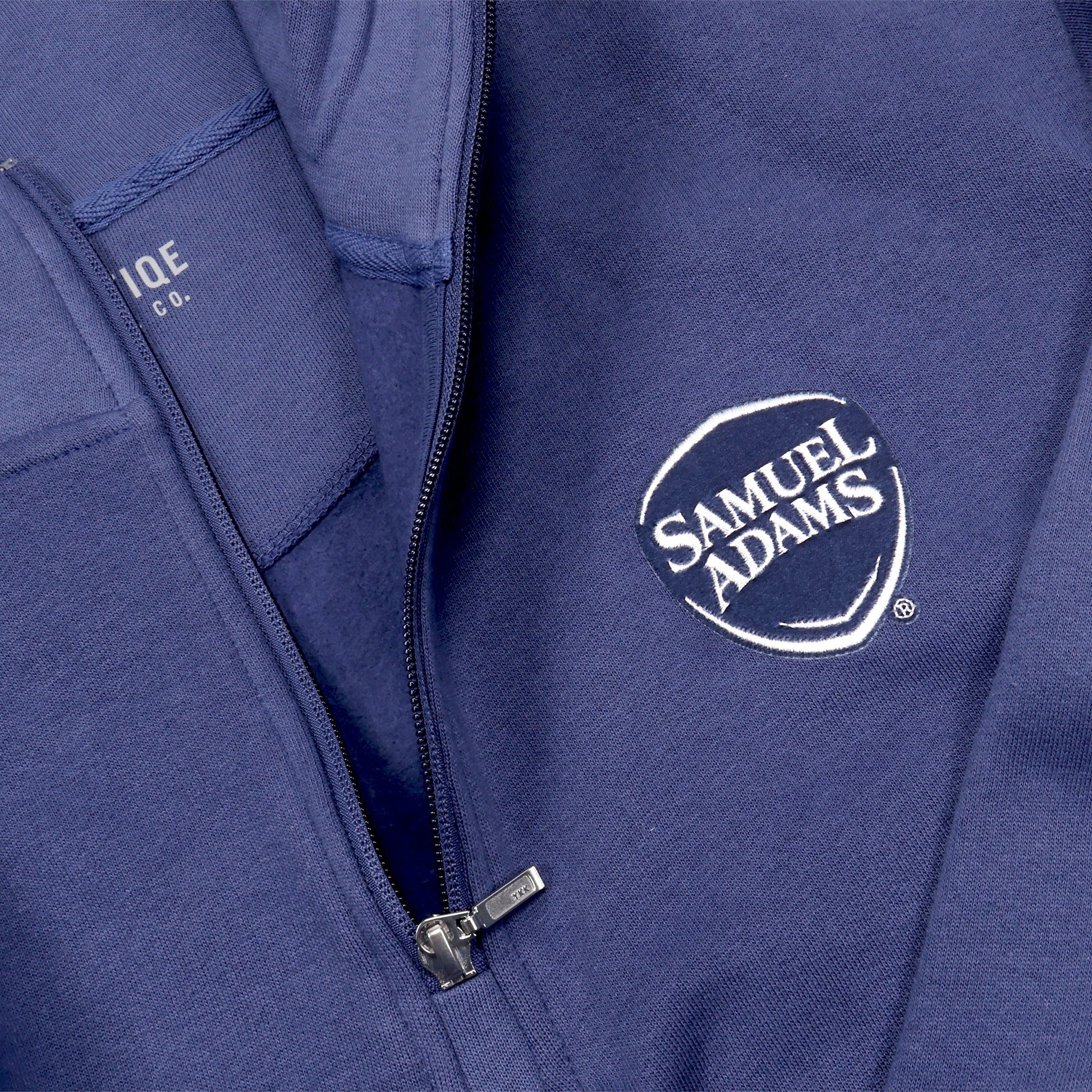 Close up of samuel adams logo on a blue quarter zip sweatshirt