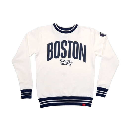 This is a white crewneck sweater with thick navy stripes around the neckband, cuff, and hem of the sweater. In matching large navy text reads "BOSTON", beneath in smaller text in the Samuel Adam's logo.