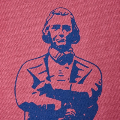 A close-up of a pink fabric surface featuring a dark blue graphic print of a historical figure with arms crossed.